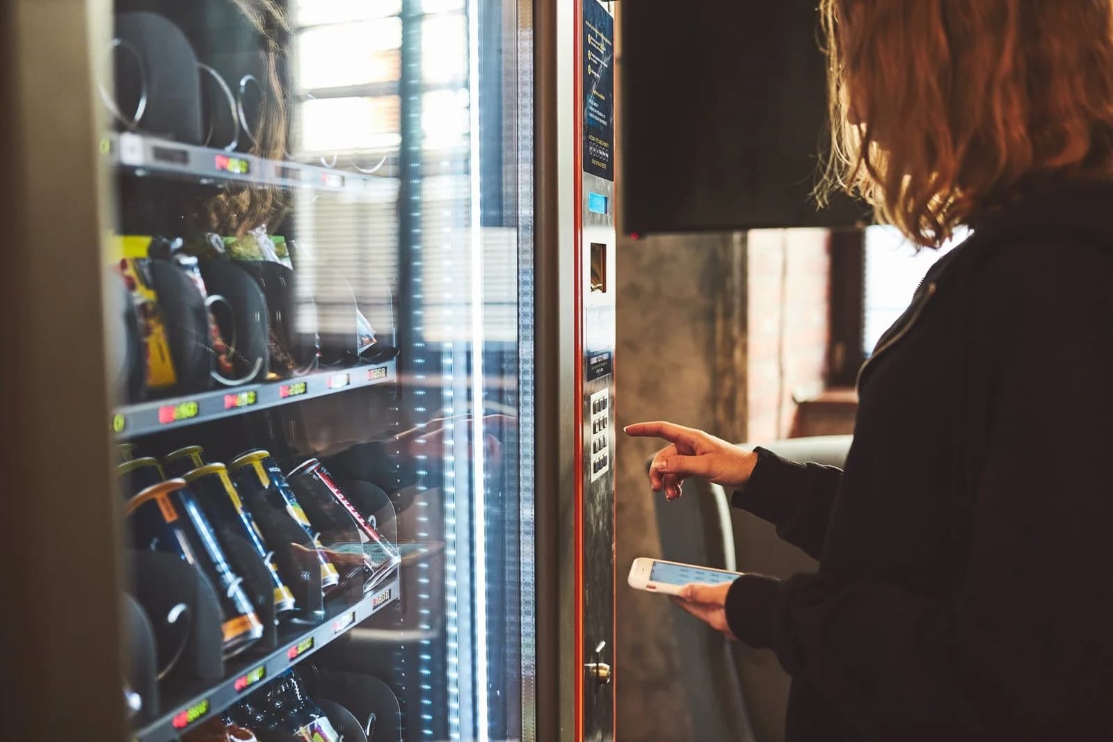 A woman paying at a vending machine with her phone